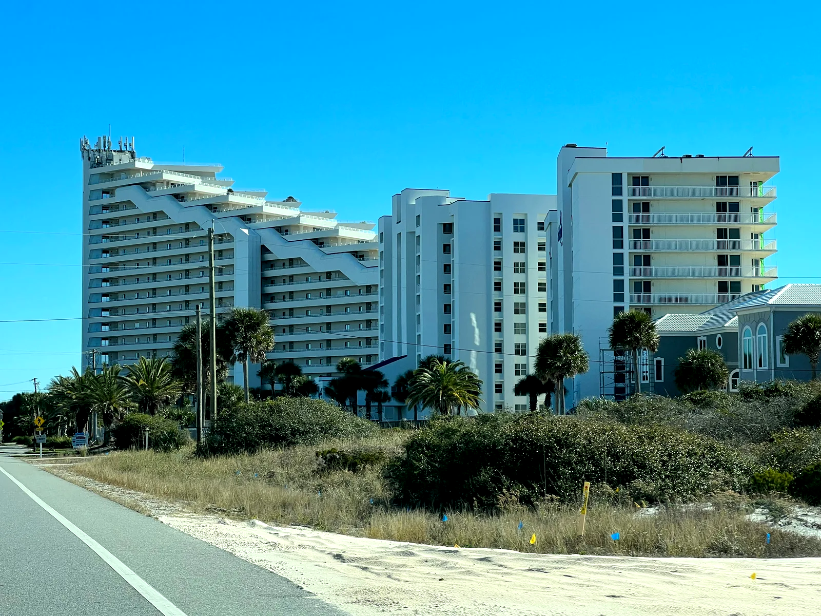 Torres de un hotel de playa entre palmeras, vistas desde la vía de acceso.